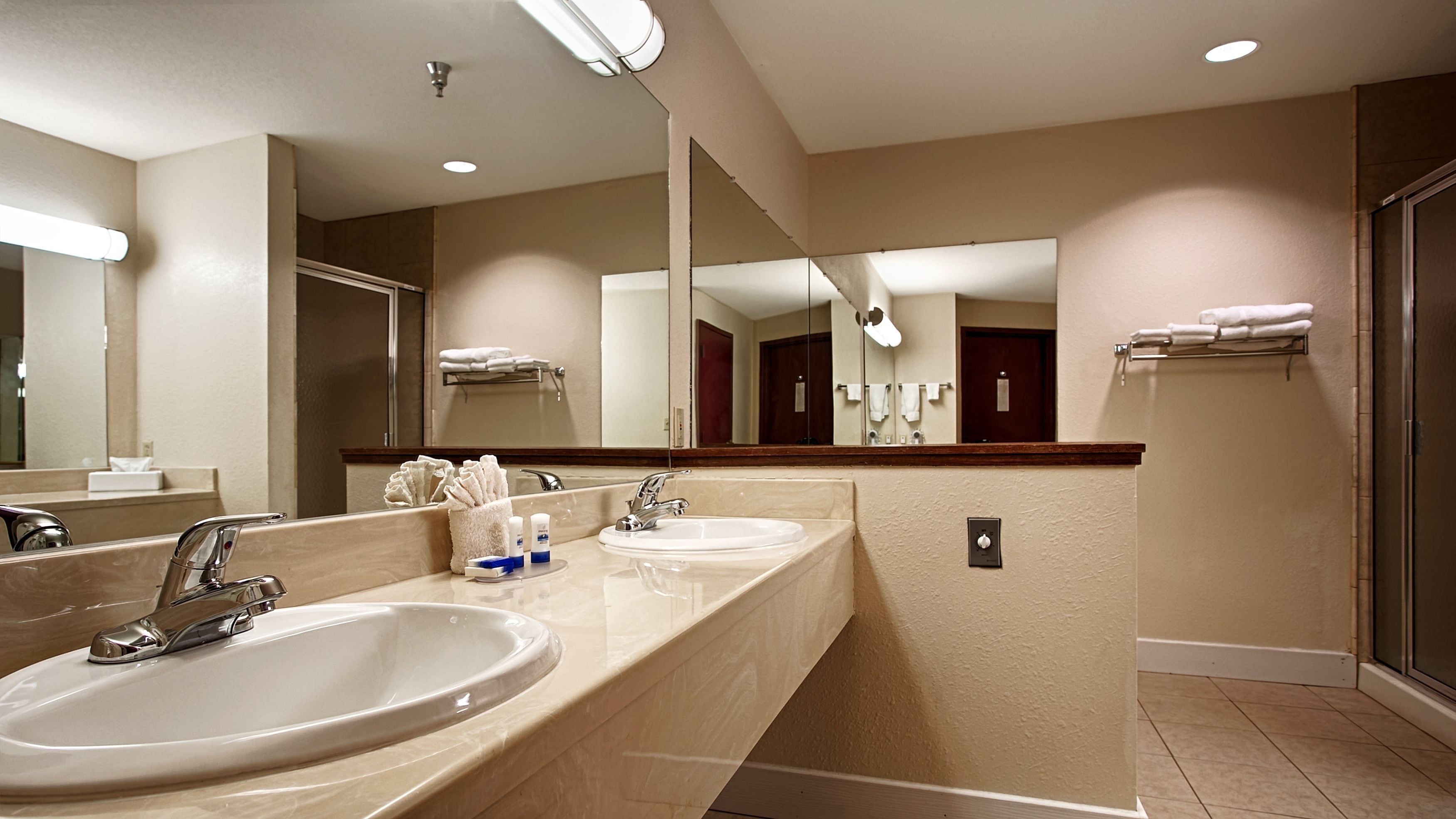 Une salle de bain d’hôtel avec deux lavabos, un grand miroir et un porte-serviettes.