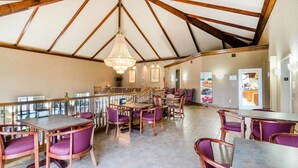 A spacious dining area with wooden beams and a high ceiling, featuring purple upholstered chairs and a central chandelier. - Quality Inn & Suites Carthage near Precious Moments Chapel (Carthage)