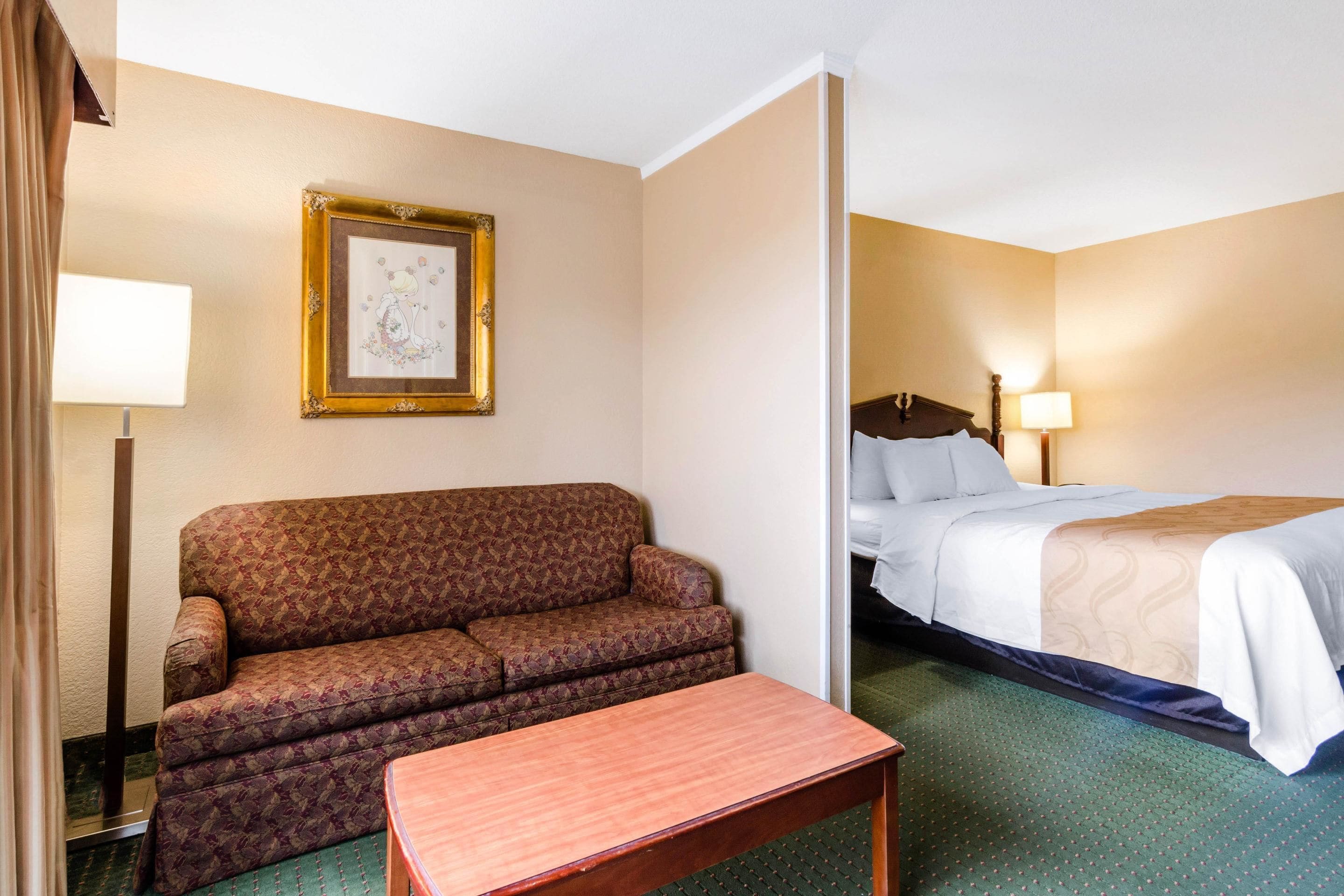 Una camera d'albergo con un divano, un tavolino e un letto.