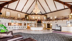 A spacious lobby with a high ceiling, a central reception desk, and a staircase leading to an upper level. - Quality Inn & Suites Carthage near Precious Moments Chapel (Carthage)