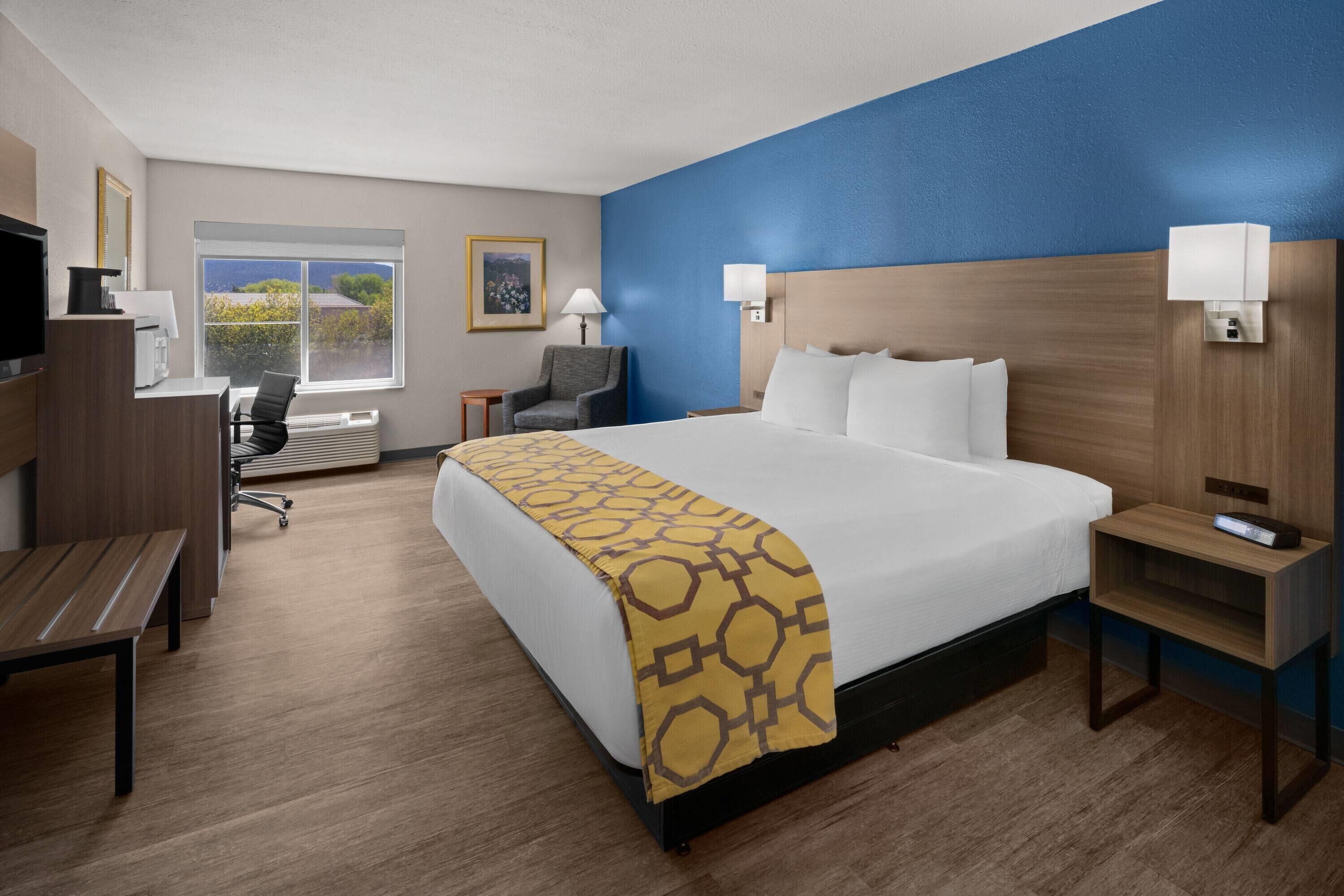 Een hotelkamer met een bed, nachtkastjes, een bureau, een stoel, een televisie en een raam met uitzicht.