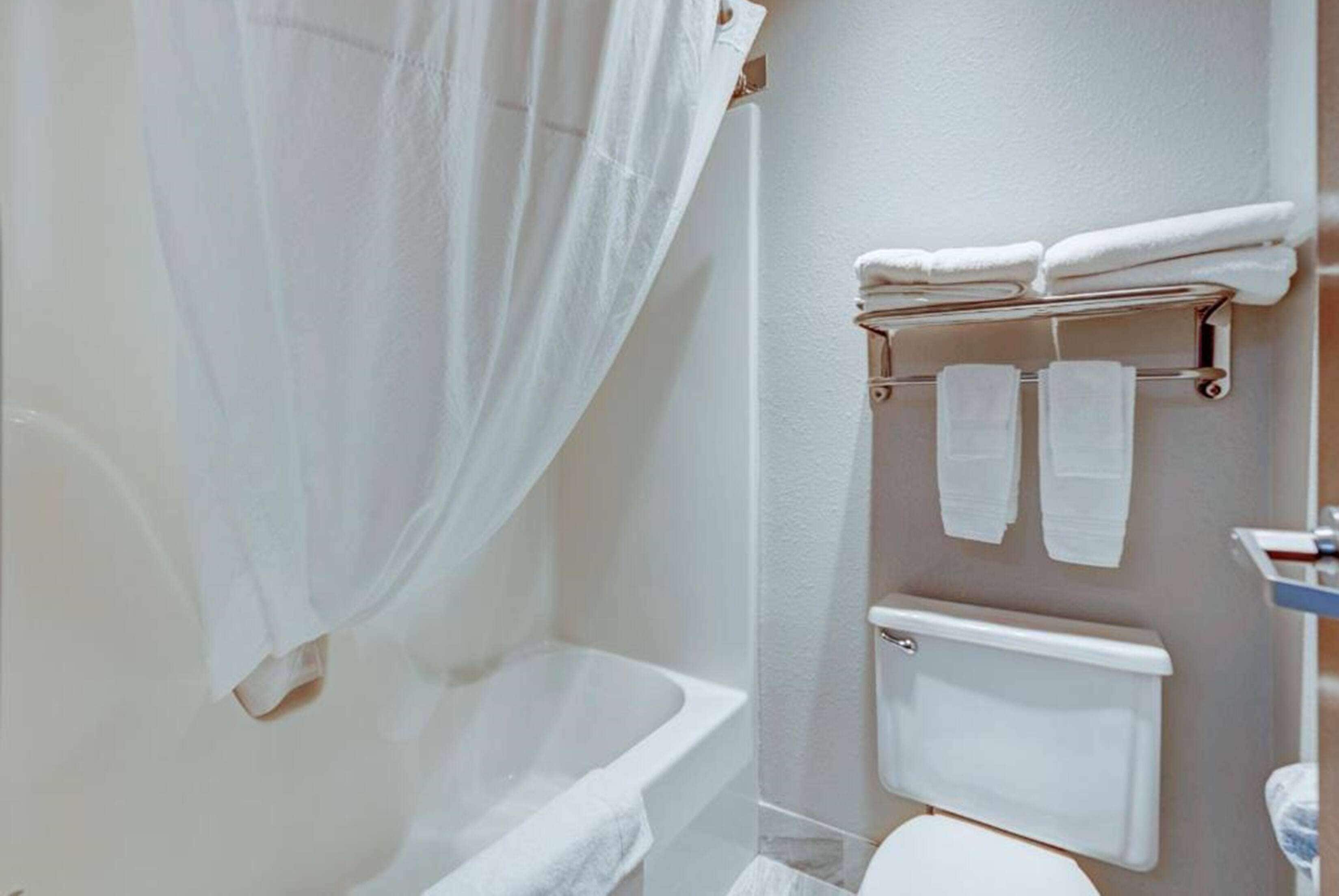 A bathroom with a bathtub, a toilet, and a towel rack with towels.
