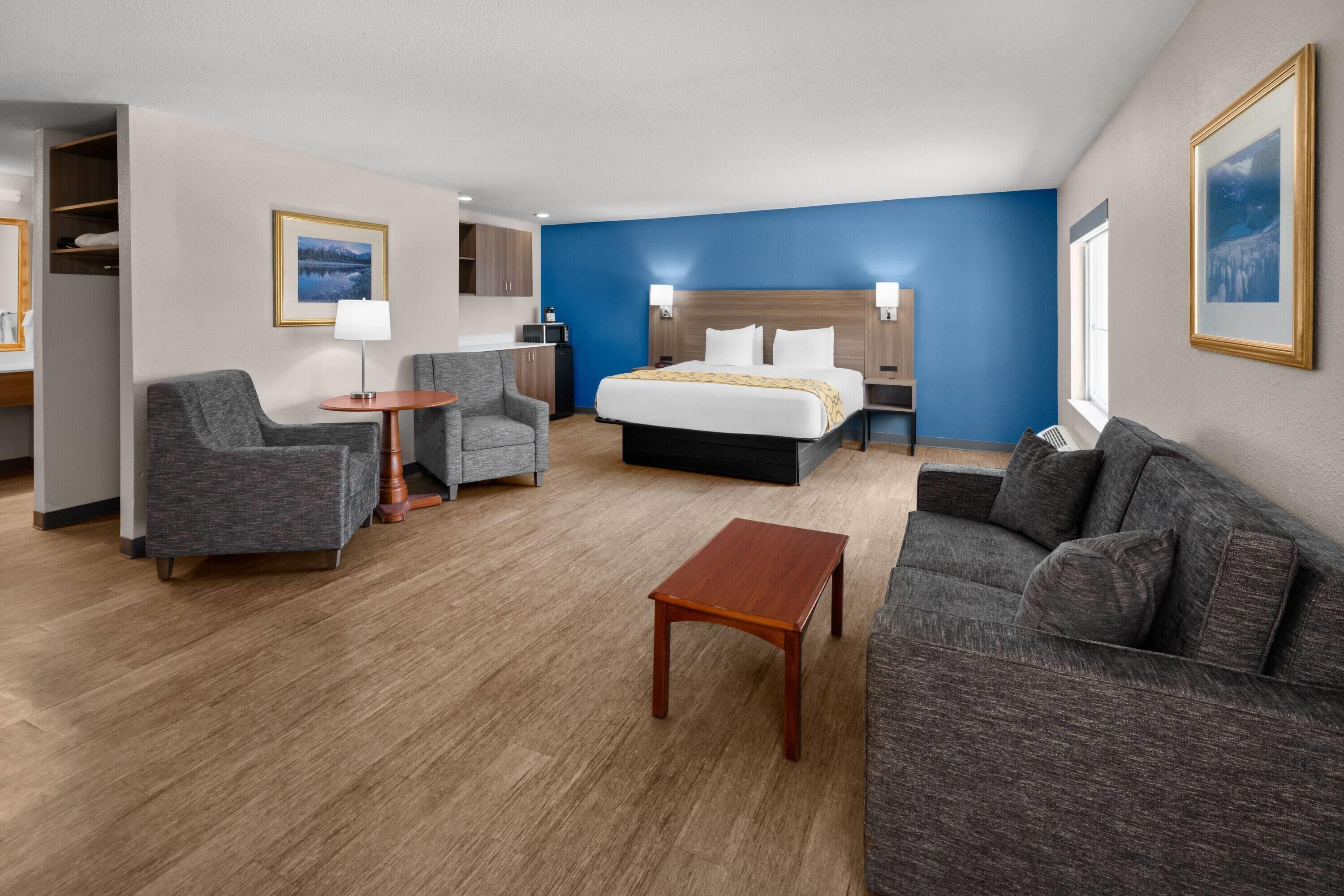 Quarto de hotel com cama, duas poltronas, mesa pequena, sofá, escrivaninha e guarda-roupa.