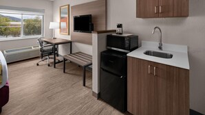 A compact kitchenette with a microwave, coffee maker, and sink.