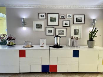 A dining area with a white table and four black chairs, a white refrigerator, and a window with blinds. at Magic Castle Hotel