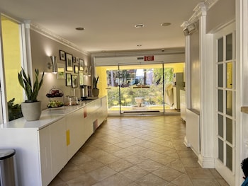 A modern bedroom with a bed, bedside tables, a TV, and a painting. at Magic Castle Hotel