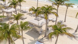 A beach with palm trees, a covered seating area, and a lounge chair. - Le Blanc Spa Resort Cancun - Adults Only - All-Inclusive (Cancun)