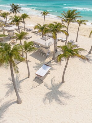 On the beach, white sand, beach cabanas, sun loungers