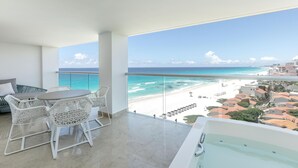 A balcony with a glass railing overlooking a beach, a white outdoor seating area, and a bathtub. - Le Blanc Spa Resort Cancun - Adults Only - All-Inclusive (Cancun)