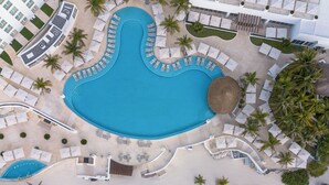 An aerial view of a resort with a large central pool, multiple smaller pools, and a beach area with sun loungers and umbrellas. - Le Blanc Spa Resort Cancun - Adults Only - All-Inclusive (Cancun)