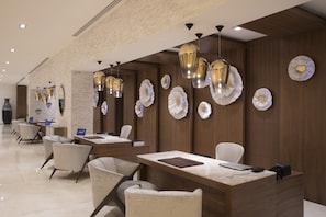 A modern hotel lobby with a reception desk, seating area, and decorative wall art.