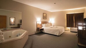 A hotel room with a large bed, a separate bathroom, a desk, and a large window with curtains.
