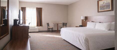 Habitación de hotel con cama, escritorio, silla y un cuadro en la pared.