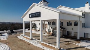 A white hotel with a covered entrance and a sign reading 'Branson Towers Hotel.'