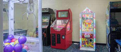 Una stanza con cabinati arcade, una macchina a grinfie e un'attrazione gioco a struttura verticale colorata.
