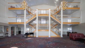 A spacious interior with a grand staircase, multiple levels, and a piano.