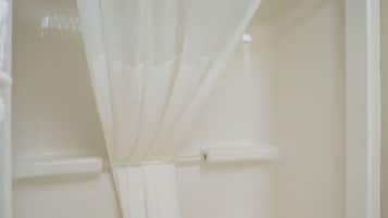 Eine weiße Badewanne mit Duschvorhang, Handtuchhalter und Duschbrause.