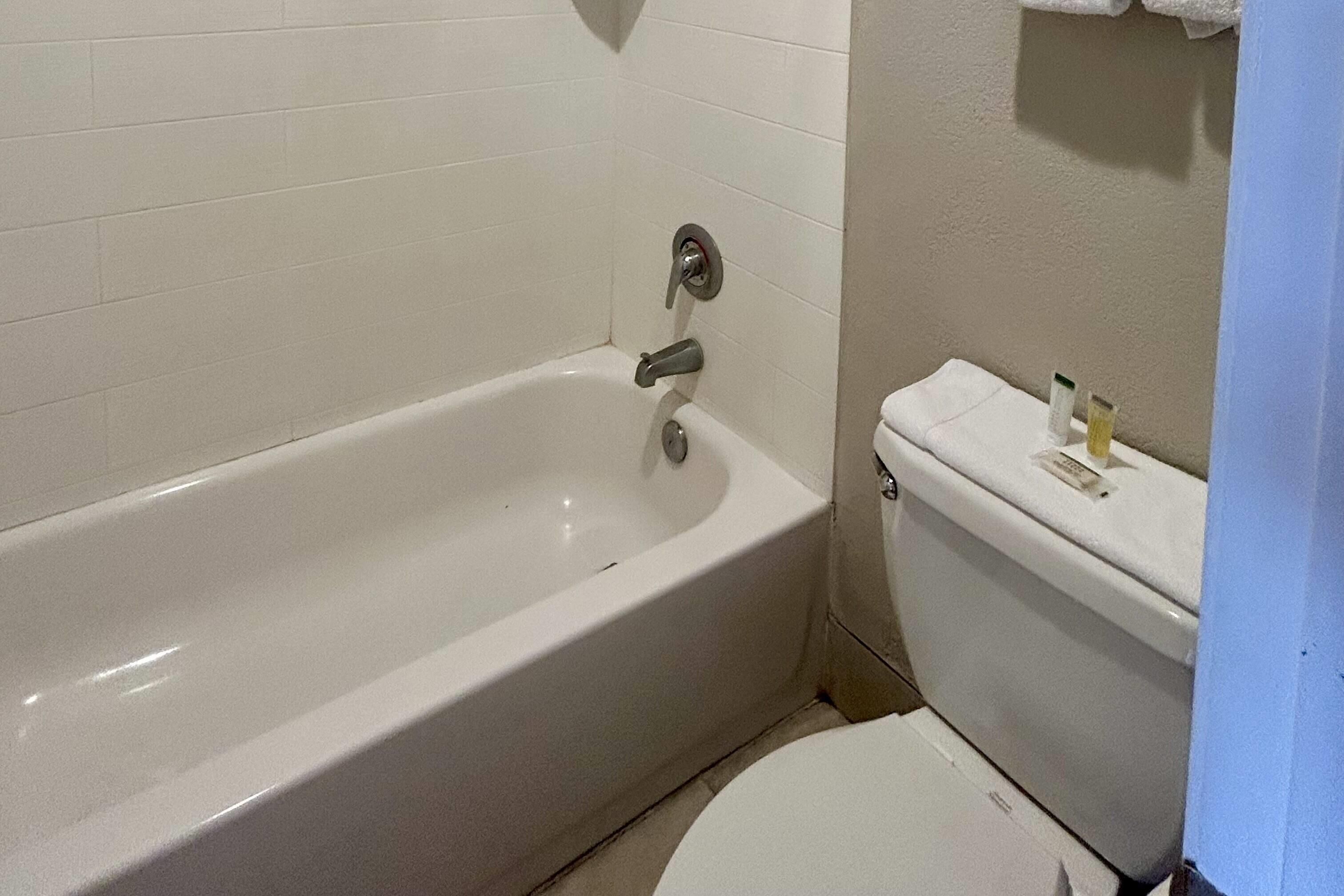 A bathroom with a white bathtub, toilet, and sink.