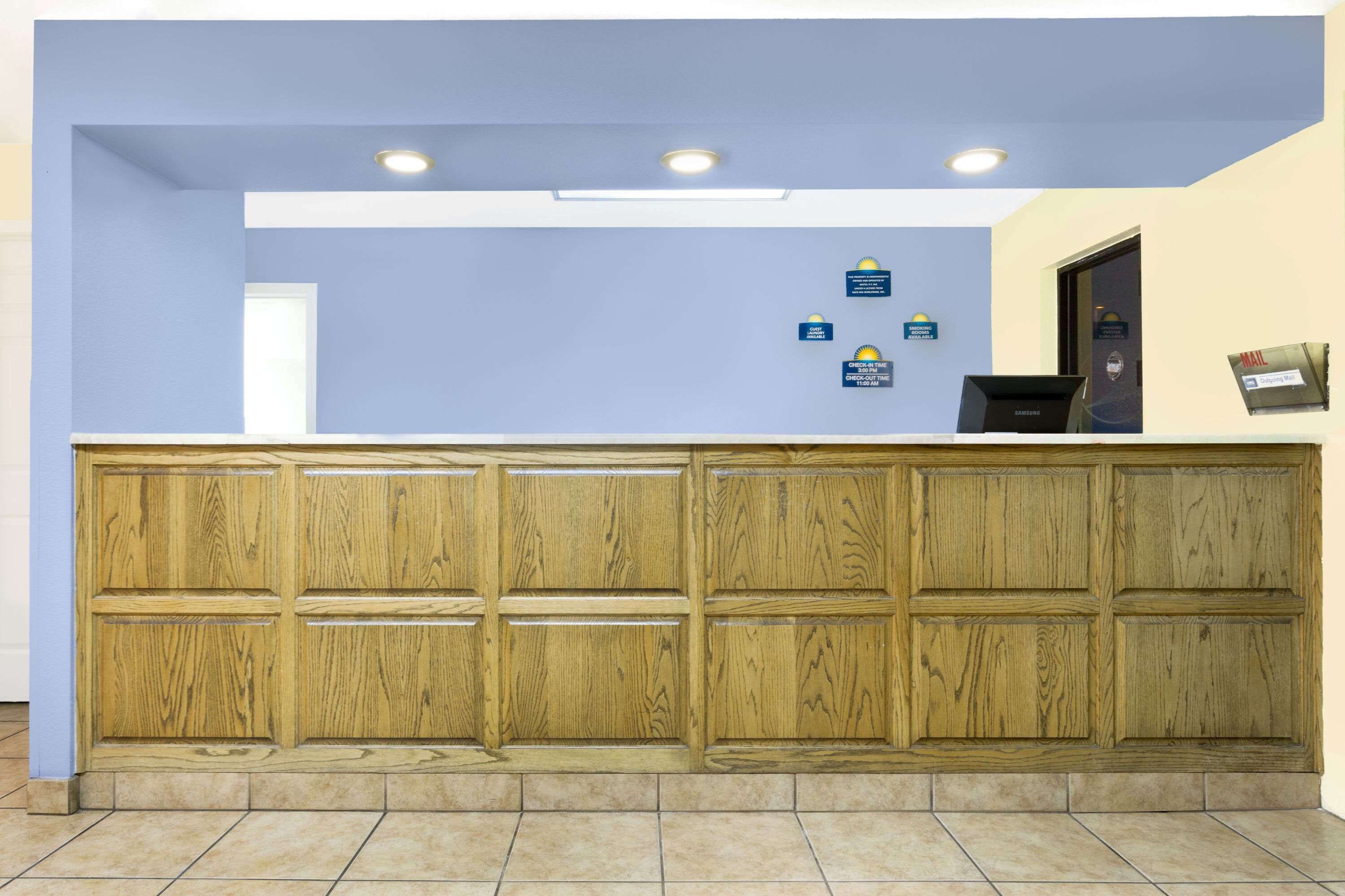 A reception desk with a wooden panel design, a blue wall, and a tiled floor.