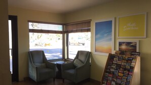 A corner seating area with two chairs, a small table, and a display of travel brochures. - Days Inn by Wyndham Kingman West (Kingman)