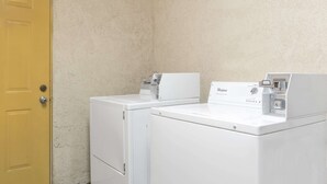 Two white Whirlpool washers in a corner with a yellow door and textured walls. - Days Inn by Wyndham Kingman West (Kingman)