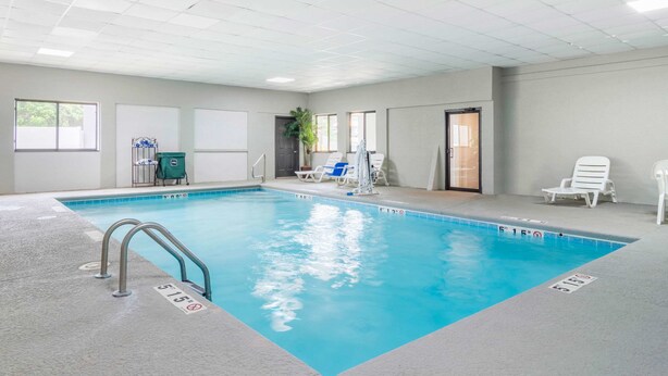 An indoor swimming pool with clear lane markings, a lifeguard chair, and a door leading to another room.