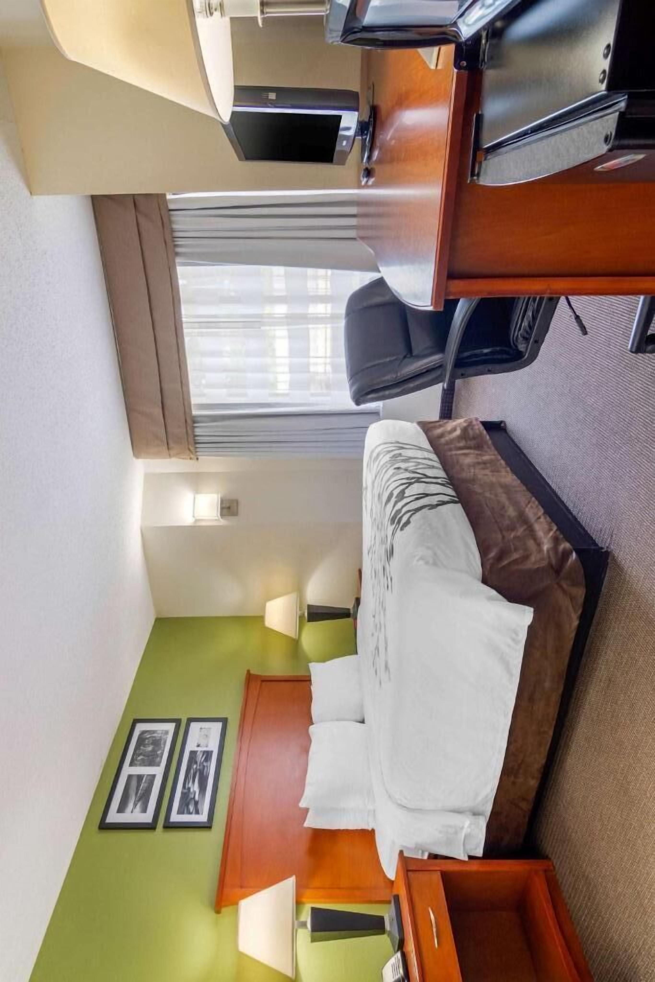 A compact room with a bed, a desk, and a window.