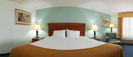 A hotel room with a large bed, two bedside tables with lamps, a chair, and two paintings on the walls.