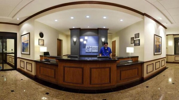 A hotel reception desk with a modern design, a digital display, and a receptionist. - Holiday Inn Express Hotel & Suites Lake Okeechobee by IHG (Okeechobee)