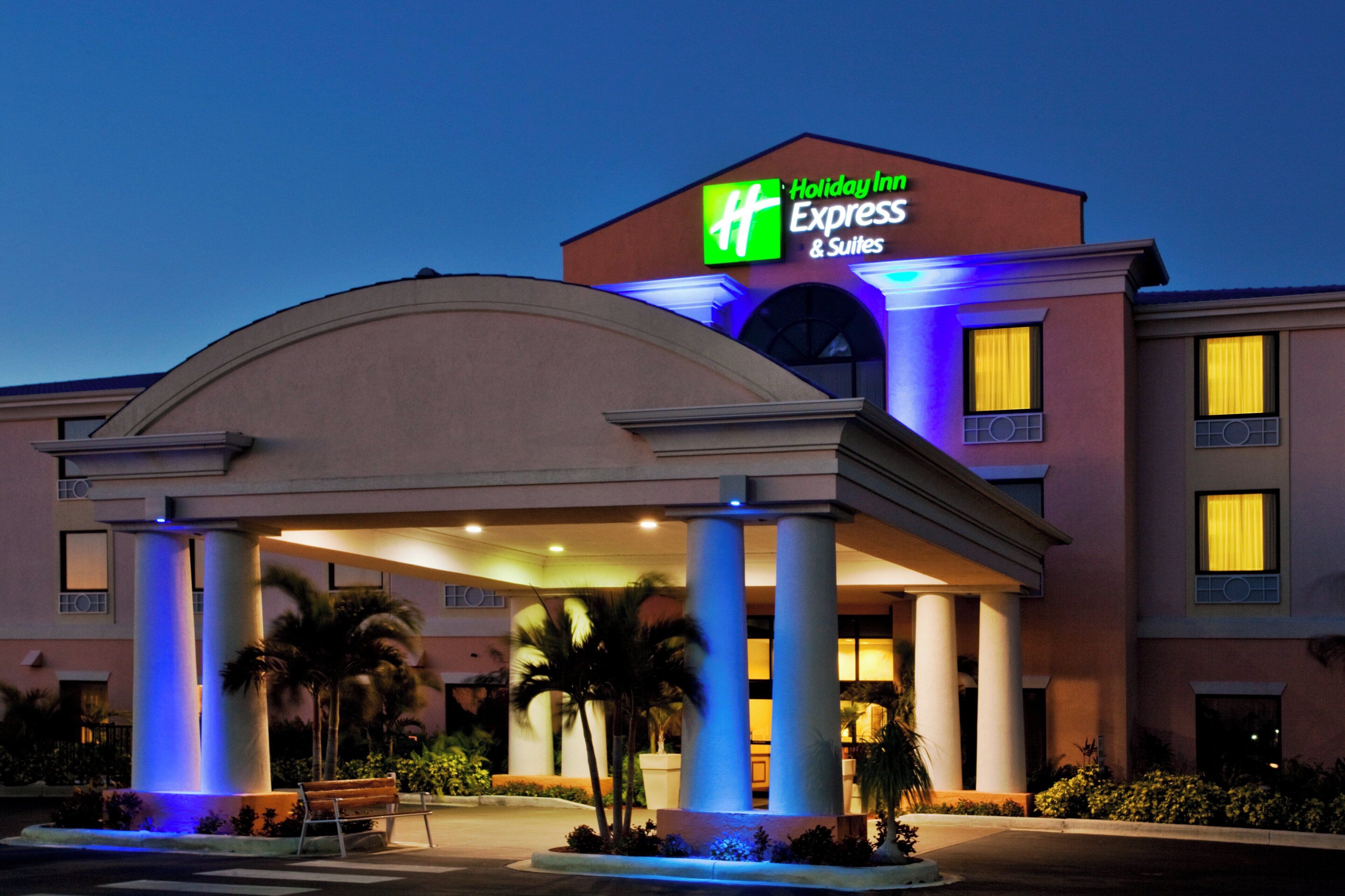 A Holiday Inn Express & Suites hotel with a covered entrance and palm trees.