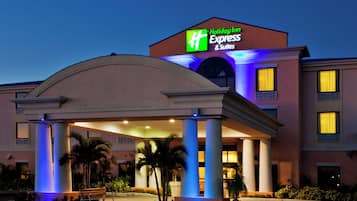 A Holiday Inn Express & Suites hotel with a covered entrance and palm trees.