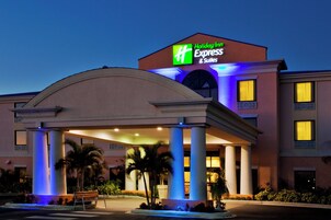 Un hotel Holiday Inn Express & Suites con entrada cubierta y palmeras.