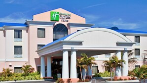 Un hôtel Holiday Inn Express & Suites, reconnaissable à son enseigne bien visible, à son entrée abritée et à son jardin aménagé.