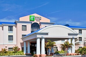 Un hôtel Holiday Inn Express & Suites, reconnaissable à son enseigne bien visible, à son entrée abritée et à son jardin aménagé.