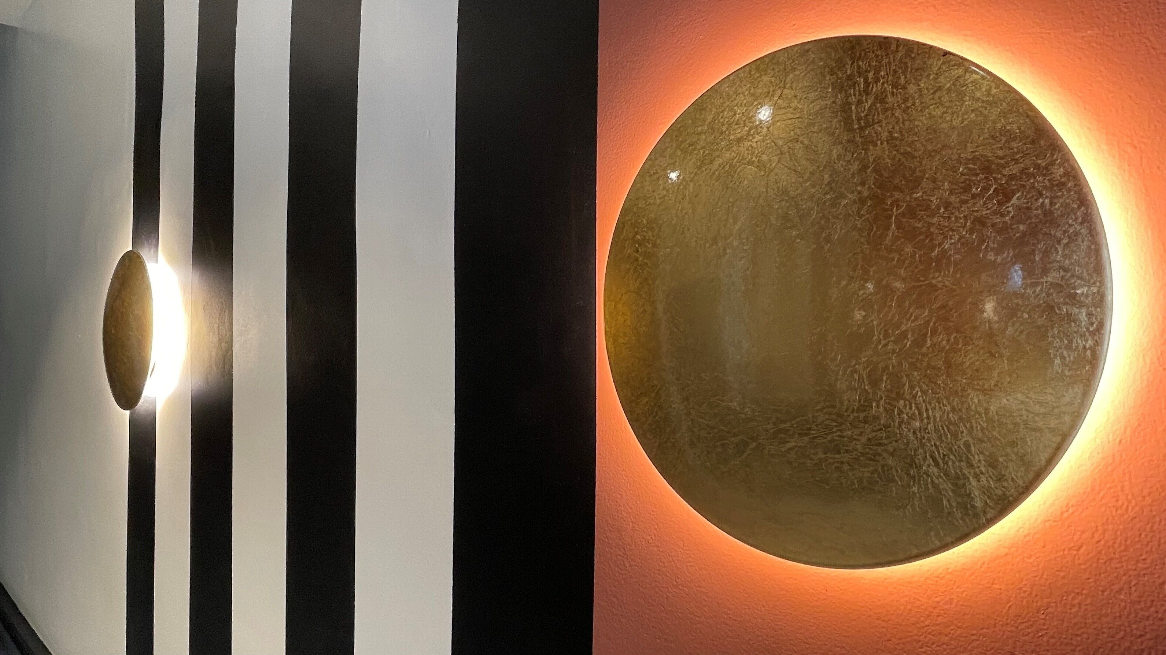 Un mur orné d’un miroir rond et de rayures verticales.