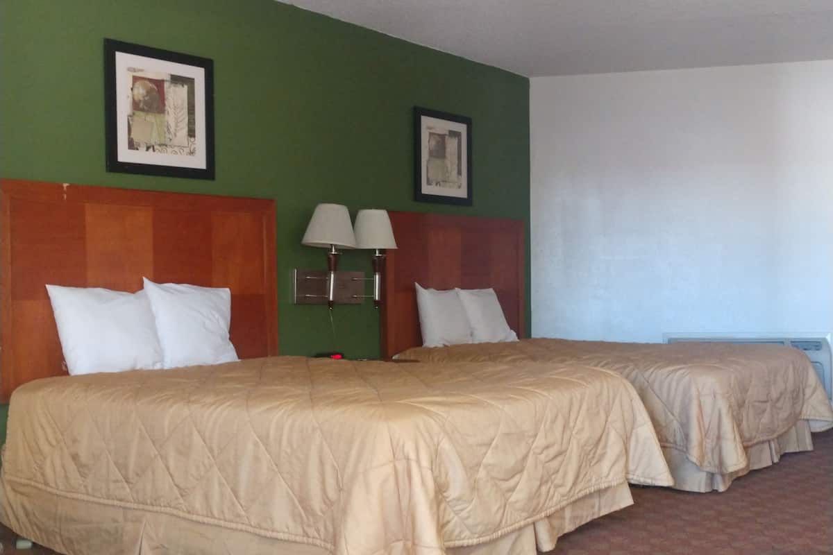 A hotel room with two beds, green walls, and framed pictures on the wall.