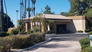 A building with a tiled roof, surrounded by palm trees and greenery.