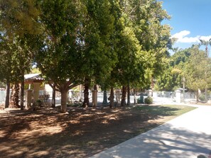 A paved pathway lined with trees and a fenced area with a gazebo. - Windemere Hotel and Conference Center (Mesa)
