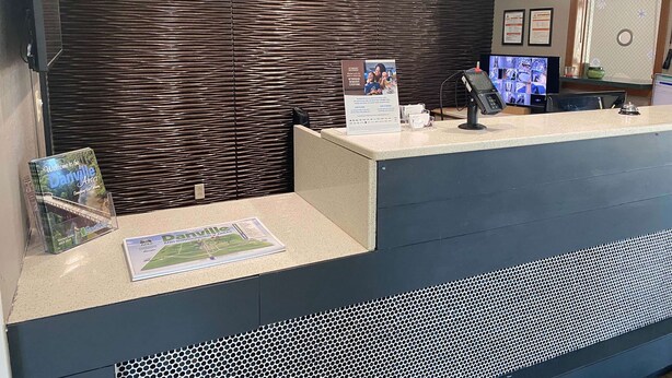 A reception desk with a digital screen, a telephone, and informational brochures.