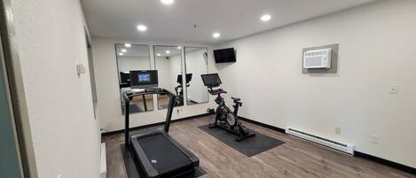 A gym with a treadmill, stationary bike, and exercise equipment.