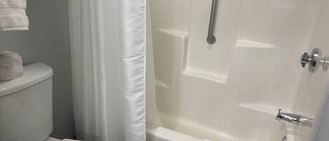 Un baño con inodoro, bañera y cortina de ducha.