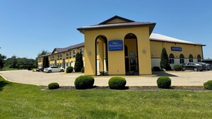 A hotel with a yellow facade, an indoor pool, and a parking lot.