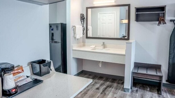 Une salle de bain moderne avec un lavabo, un miroir et un porte-serviettes.