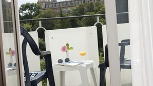 A balcony with a view of a historic building, a small table with a drink and sunglasses, and a chair. - Maritim Hotel Bad Wildungen (Bad Wildungen)