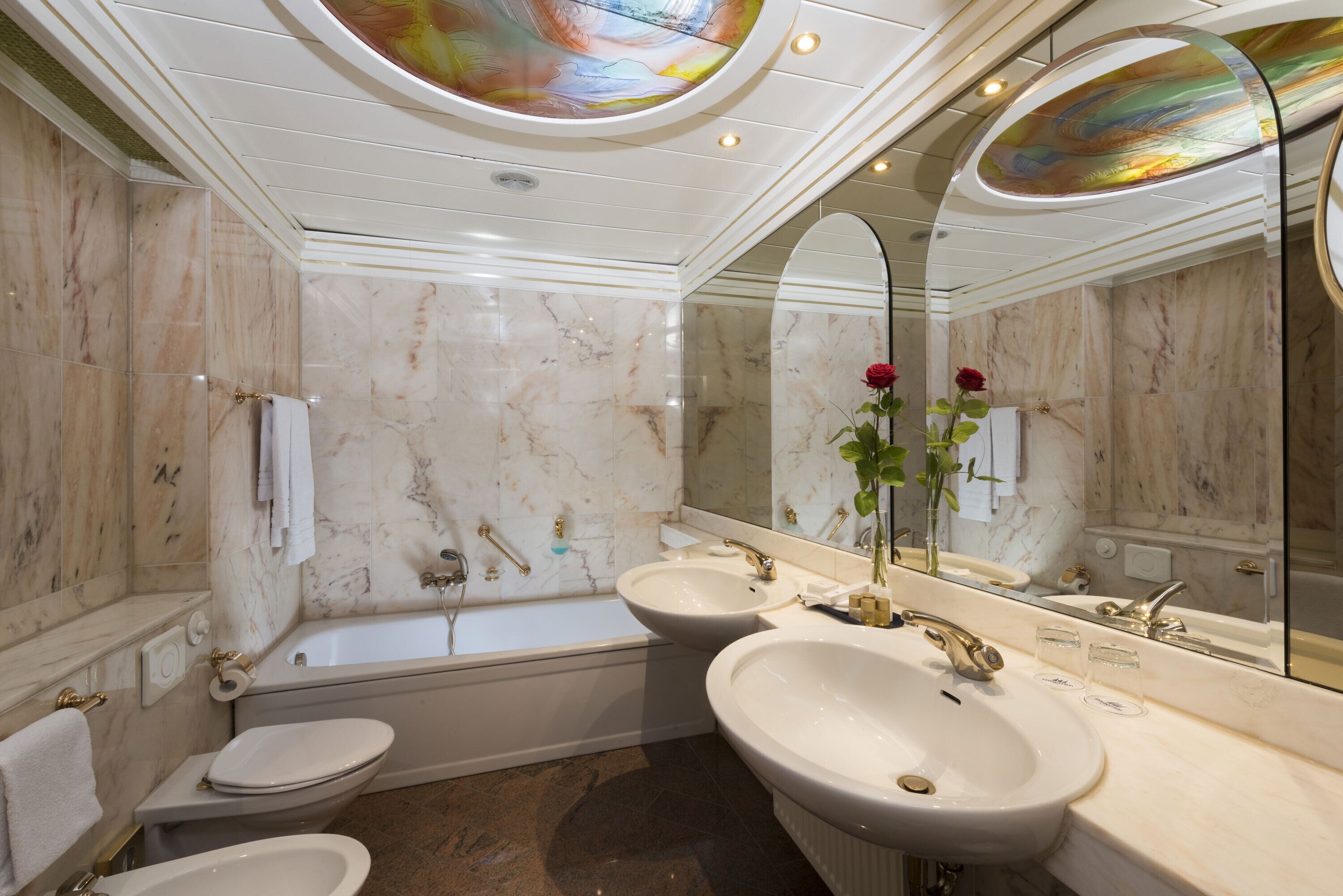 Un baño con bañera, dos lavamanos y un inodoro.