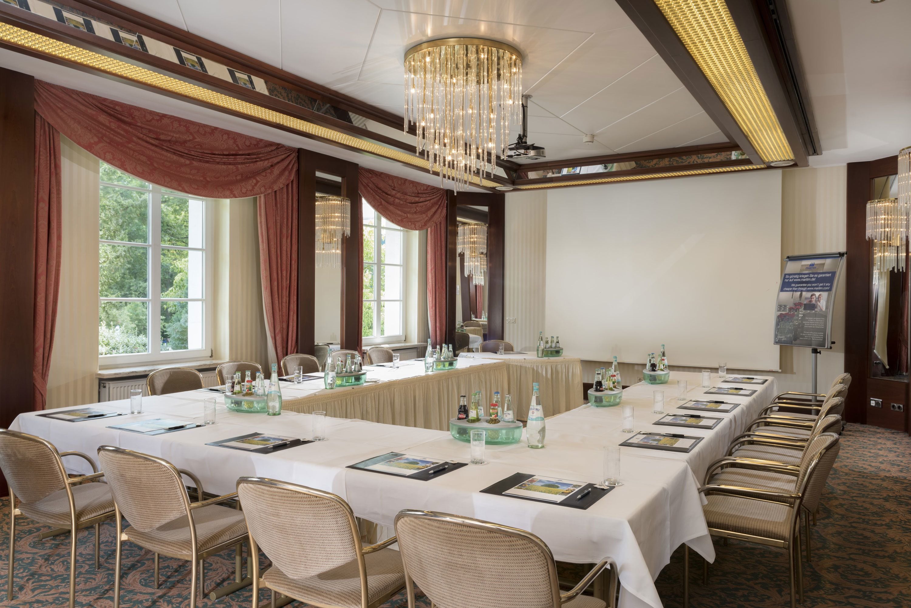A conference room with a long table, chairs, and a projector screen.