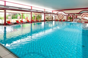 An indoor swimming pool with clear blue water, red and white poolside chairs, and a red and white architectural design. - Maritim Hotel Bad Wildungen (Bad Wildungen)