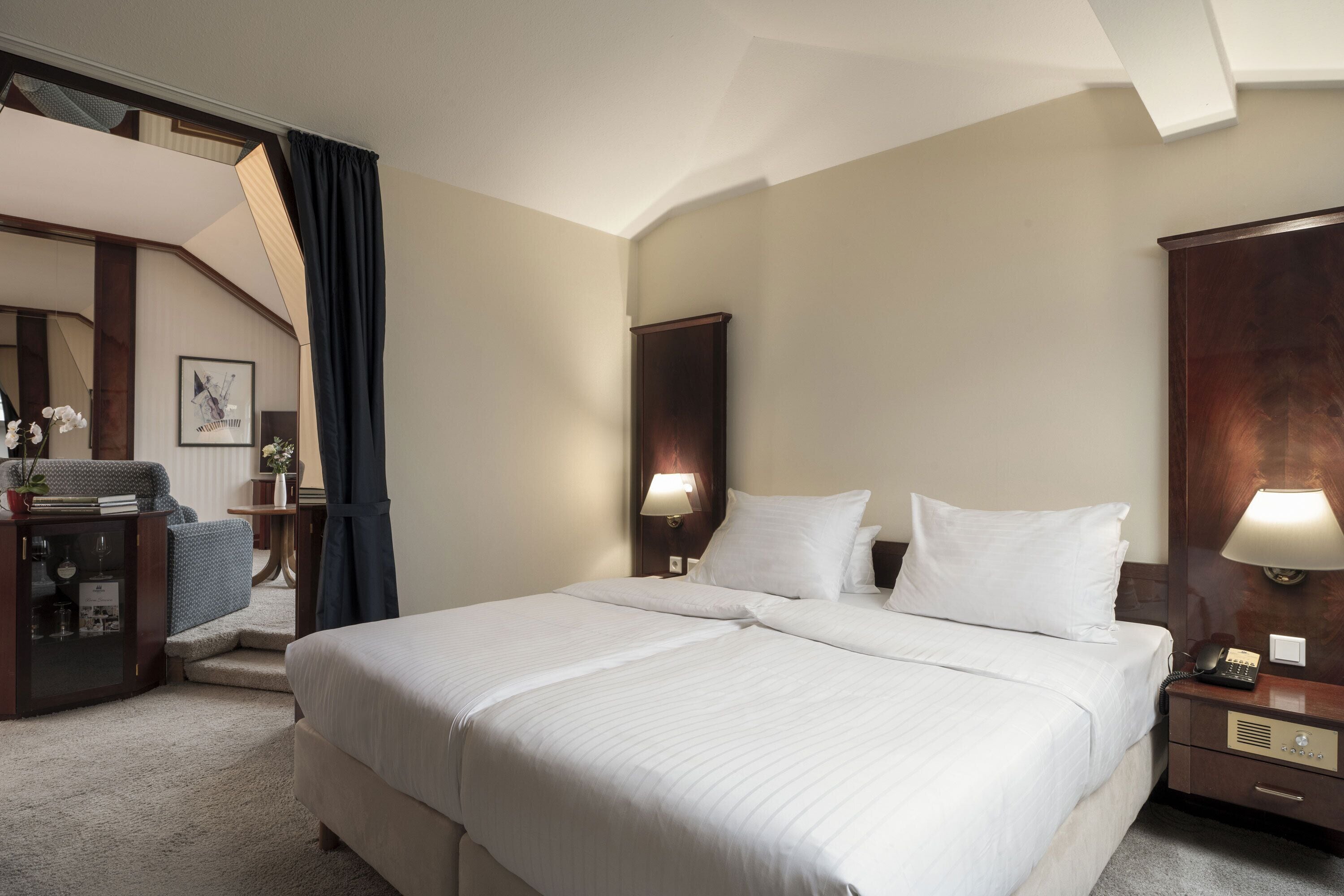 Habitación de hotel con una cama grande, un escritorio con lámpara, un teléfono y vistas a una escalera.