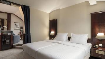 Habitación de hotel con una cama grande, un escritorio con lámpara, un teléfono y vistas a una escalera.