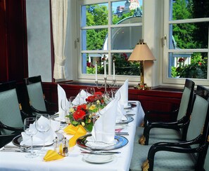A dining table set for a meal with chairs, a lamp, and a view of greenery outside. - Maritim Hotel Bad Wildungen (Bad Wildungen)